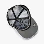 An overhead view of a gray snapback cap with a black brim, black mesh back panels, and a black adjustable strap. The inside of the cap features a detailed graphic print with the text 'MAKE YOUR BACK' and a circular logo on the brim.
