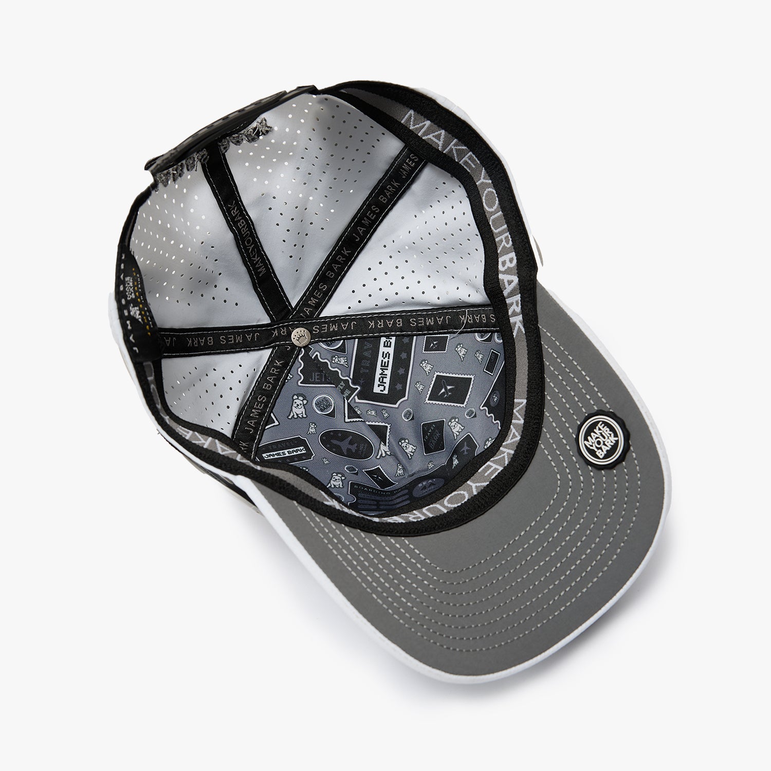 An overhead view of a gray snapback cap with a black brim, black mesh back panels, and a black adjustable strap. The inside of the cap features a detailed graphic print with the text 'MAKE YOUR BACK' and a circular logo on the brim.