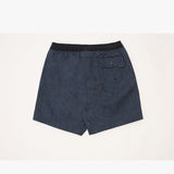 A pair of dark navy blue swim trunks with a subtle tonal pattern, featuring a black elastic waistband and a side pocket with a small black brand tag