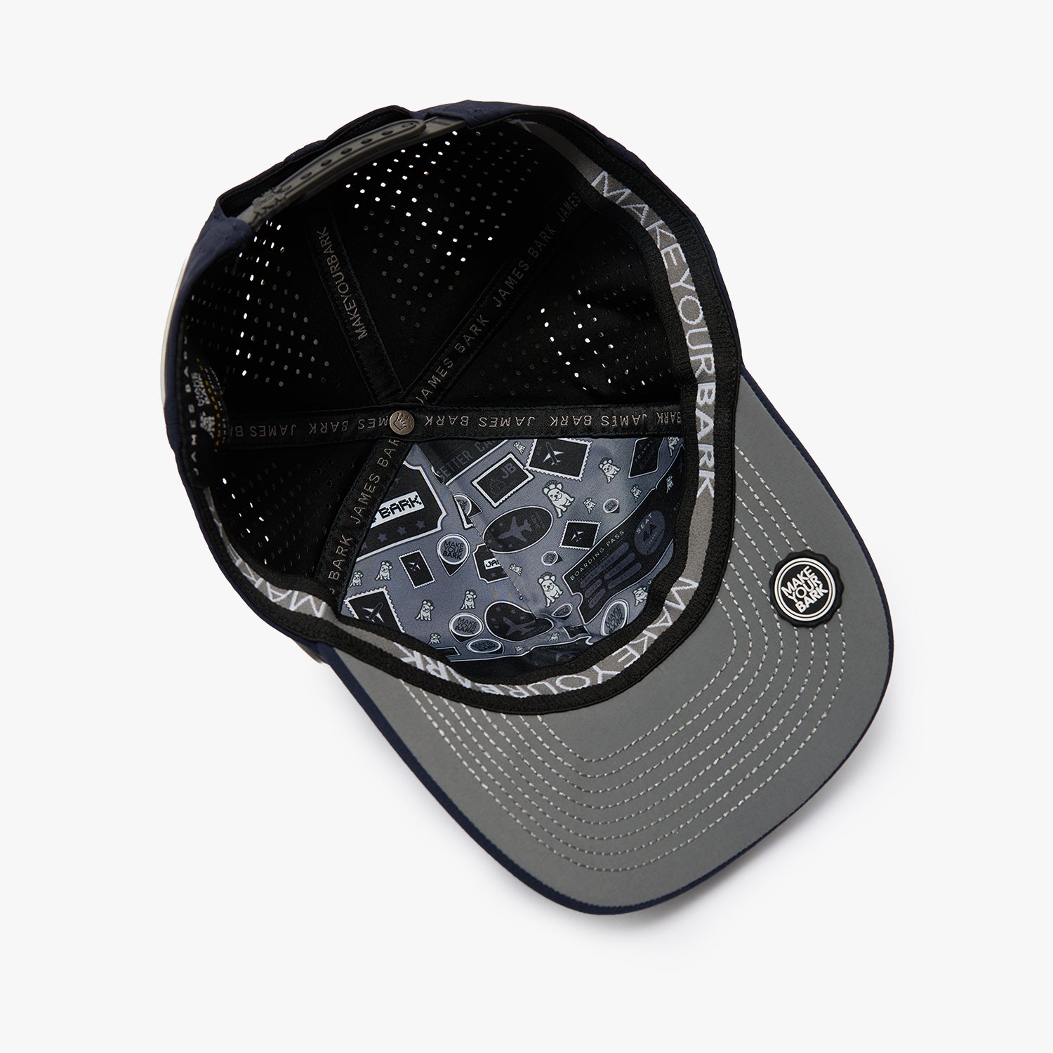 A black and gray baseball cap shown from an overhead angle, featuring a black mesh back, a gray visor with a subtle geometric pattern, and a circular patch on the side