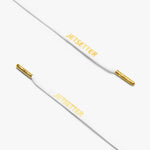 Close-up of white shoelaces with gold aglets and "Jetsetter" text