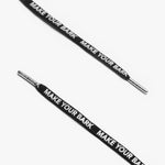 Close-up of black shoelaces with silver aglets and "MAKE YOUR BARK" text