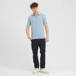 Man wearing a light blue polo shirt and black pants on a white background