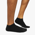 Black ankle socks worn by a person on a white background