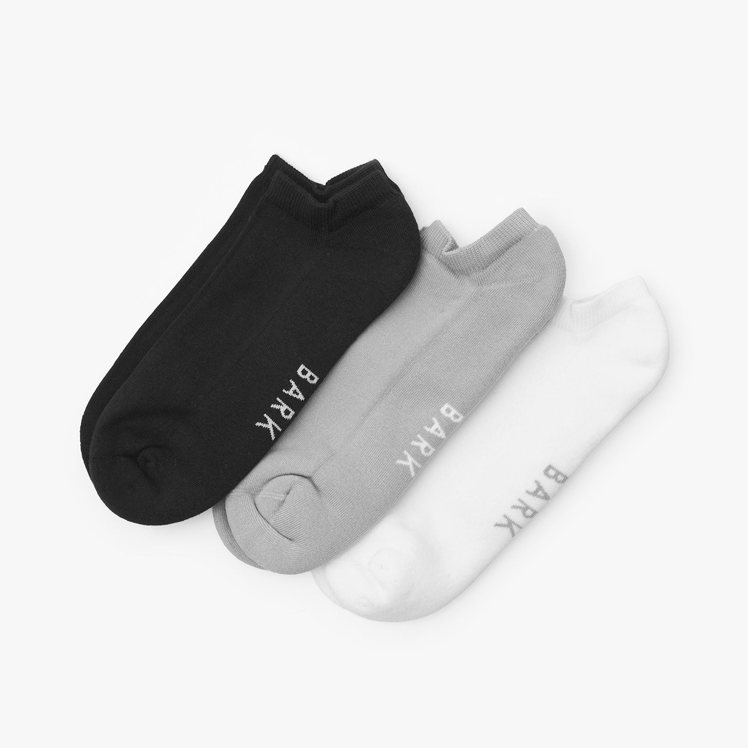 Three pairs of socks in black, gray, and white with 'BARK' branding on a light gray background.