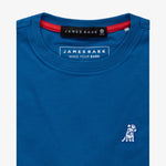 Close-up of the collar area of the blue t-shirt, showing the small white embroidered logo on the chest.