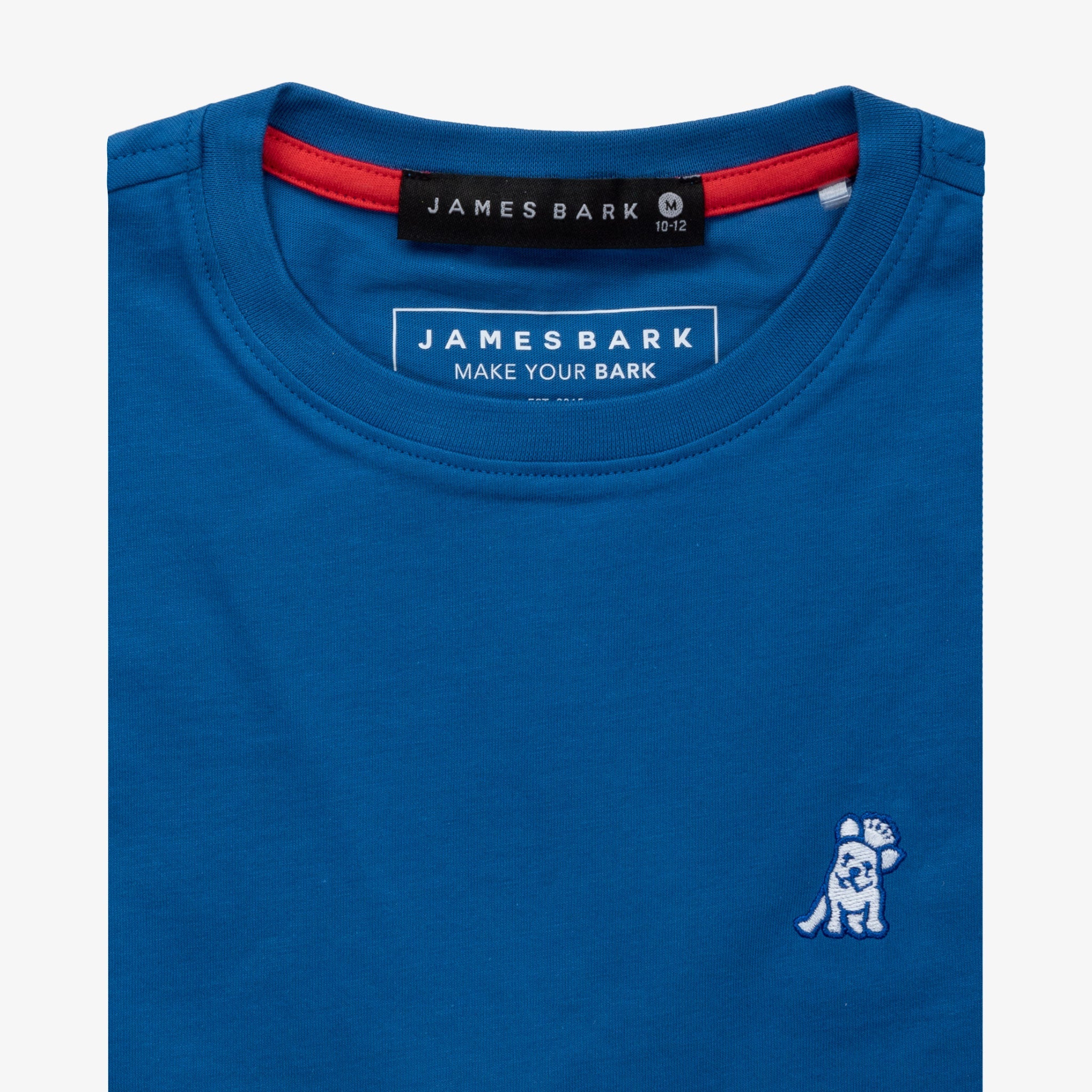 Close-up of the collar area of the blue t-shirt, showing the small white embroidered logo on the chest.