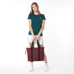 Full-body front view of a model wearing a green t-shirt and white shorts, holding a large burgundy James Bark tote bag