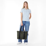 Woman holding a green tote bag against a white background