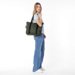 Side view of a woman holding a green tote bag on a white background