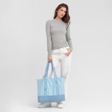Woman holding a blue tote bag with 'James Bark' branding against a light gray background