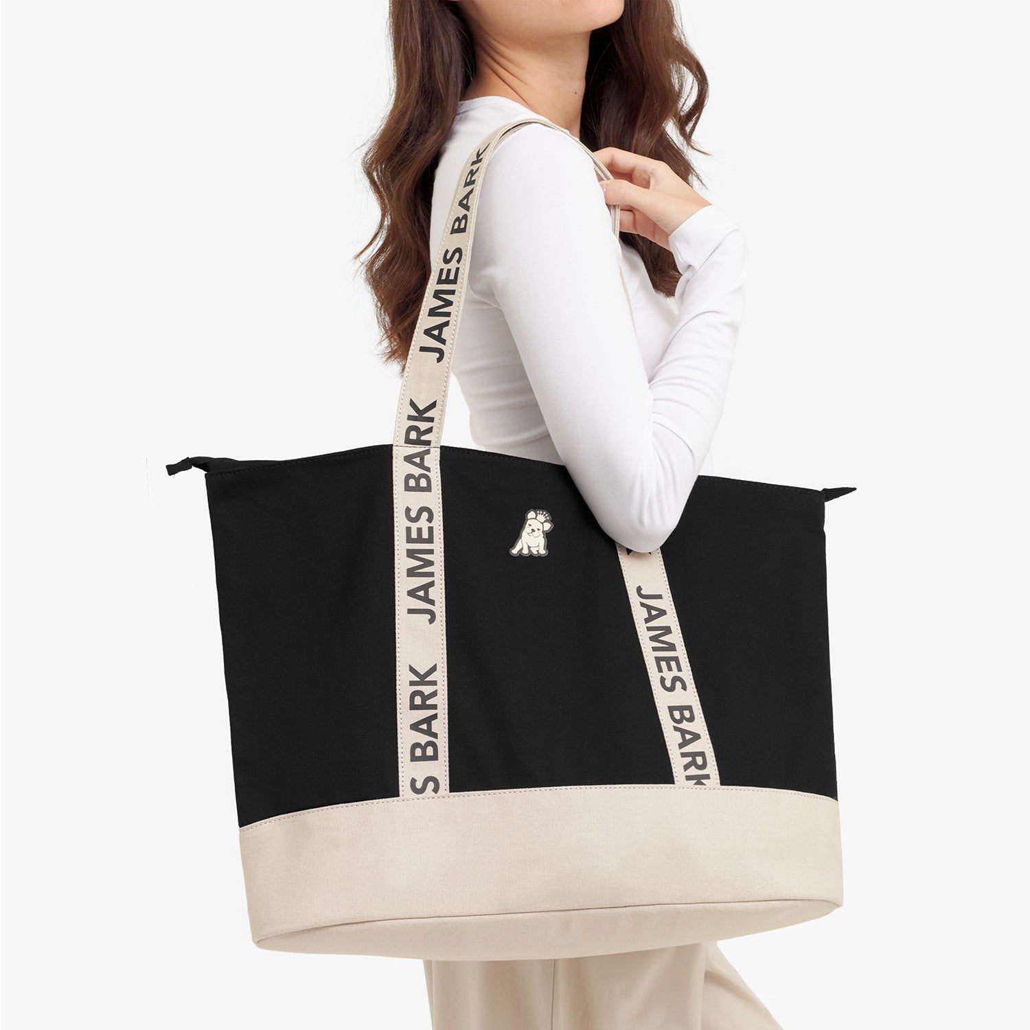Person holding a black tote bag with 'JAMES BARK' branding