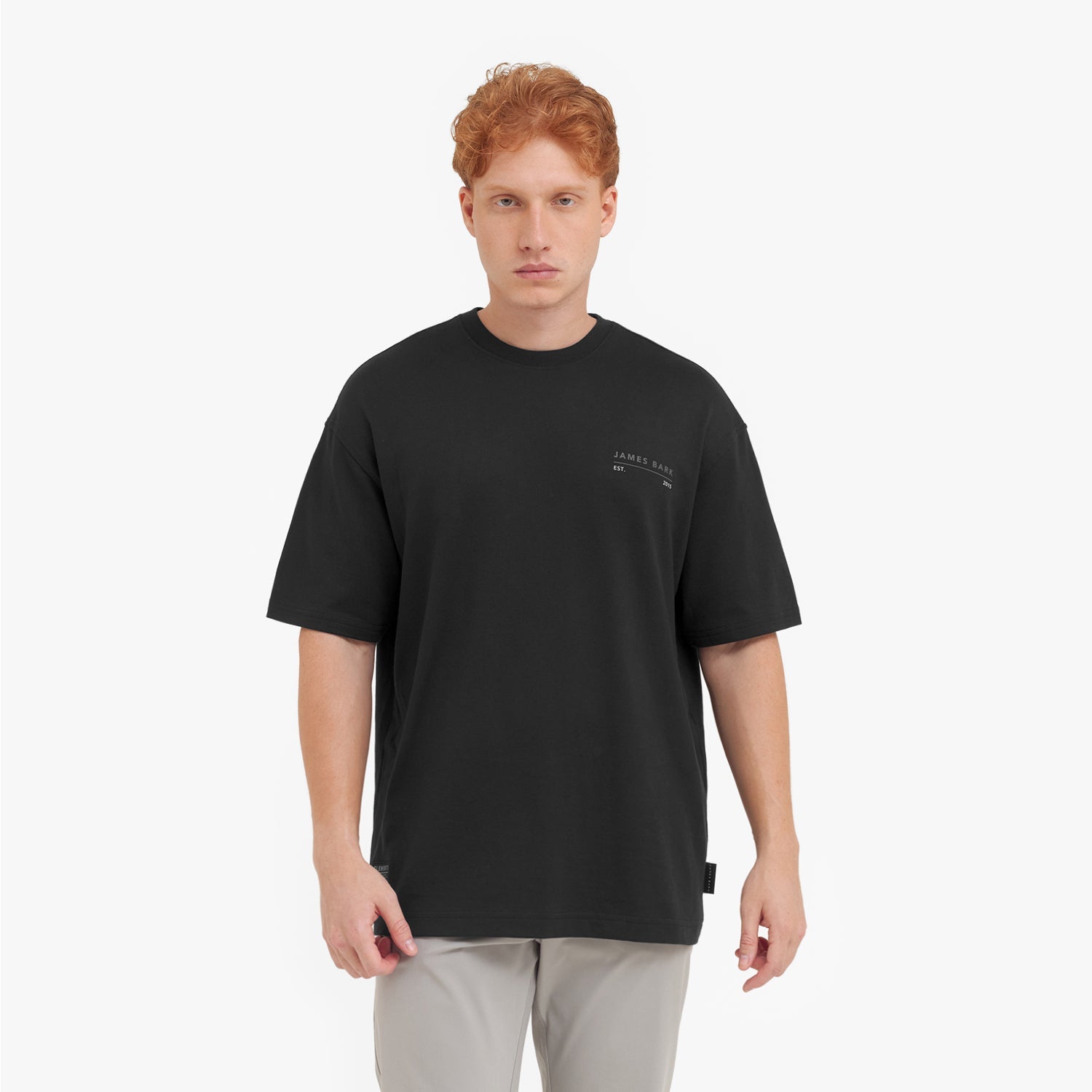 Man wearing a black t-shirt with a small logo on a white background