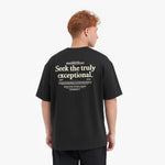 A male model with red hair wearing an oversized black t-shirt and black pants, looking forward