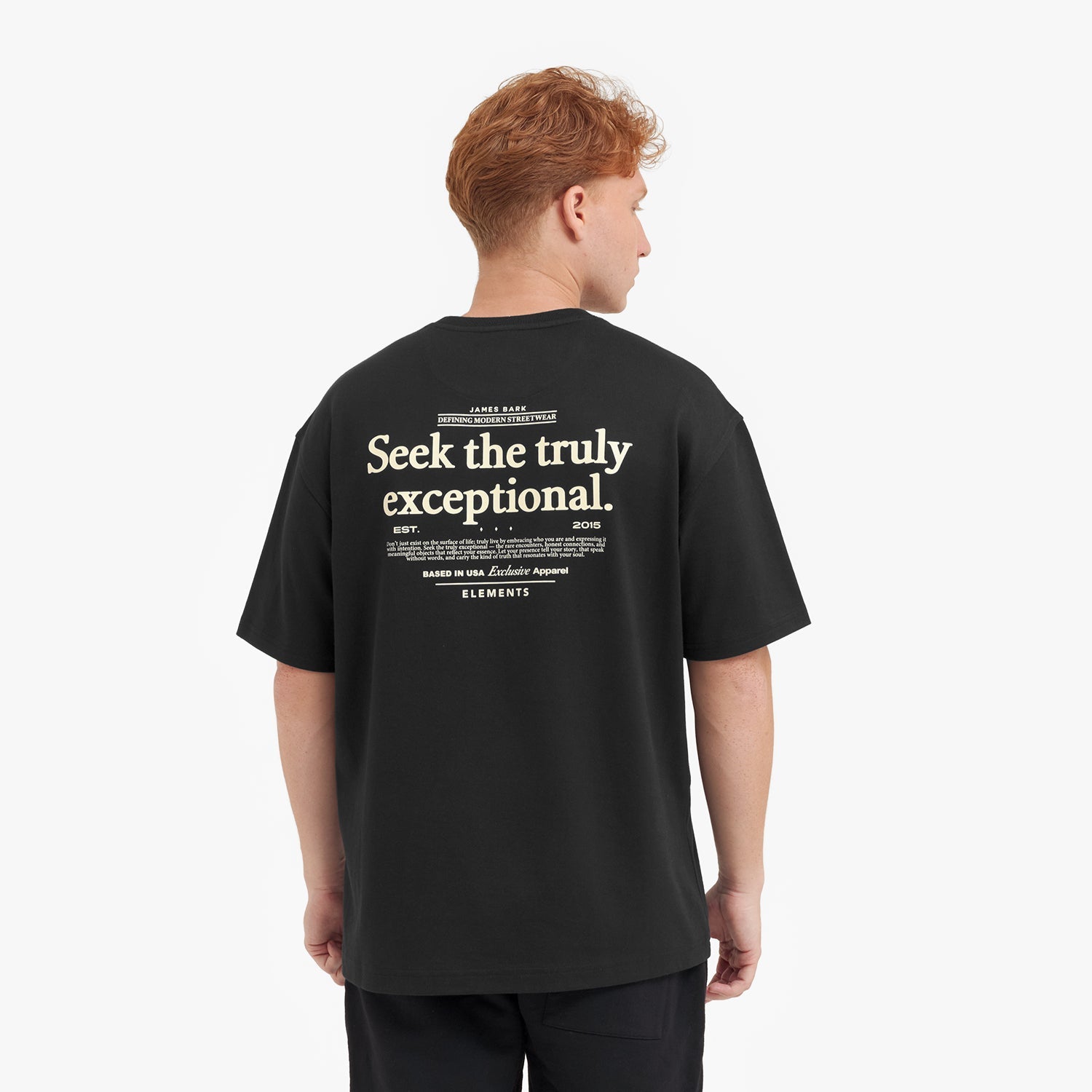 A male model with red hair wearing an oversized black t-shirt and black pants, looking forward