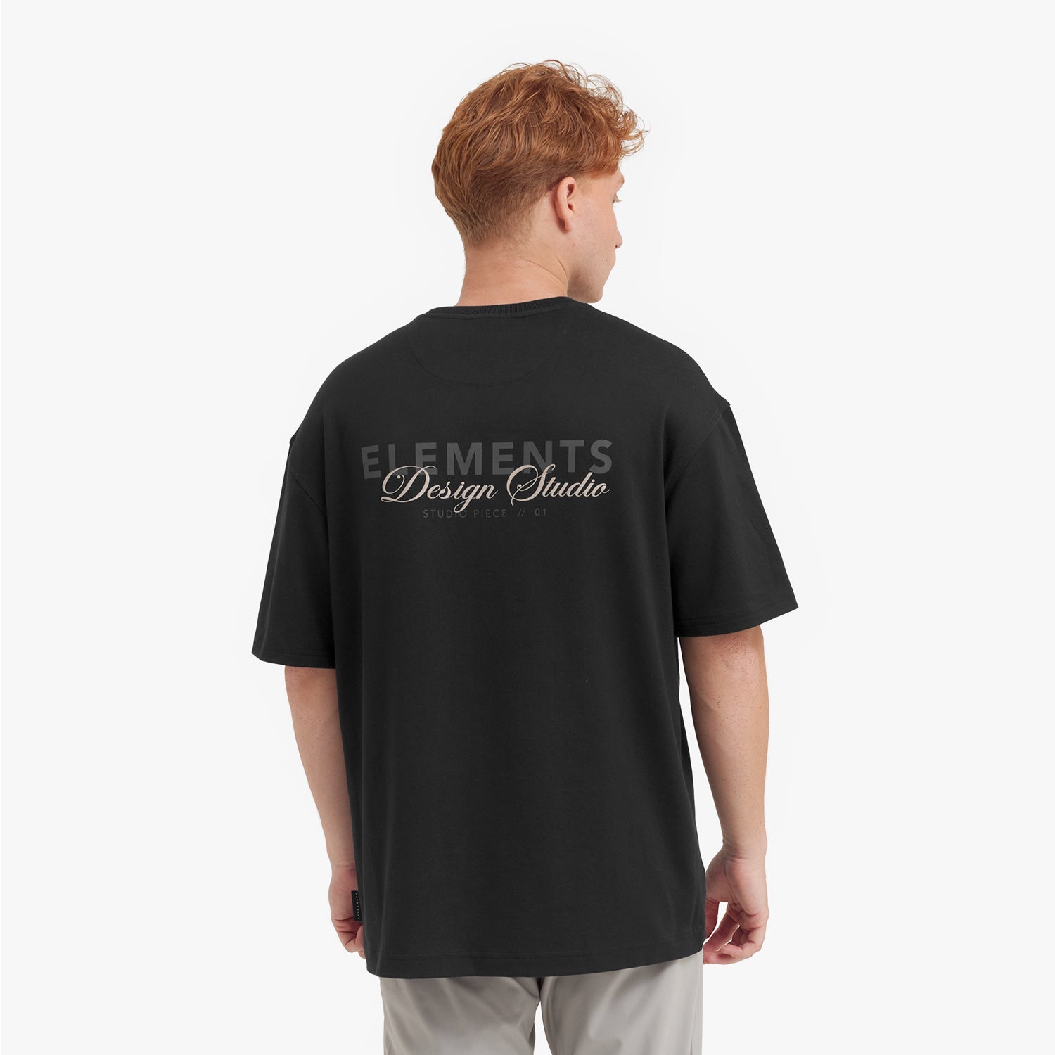 Person wearing a black t-shirt with 'Elements Design Studio' text on the back, standing against a white background