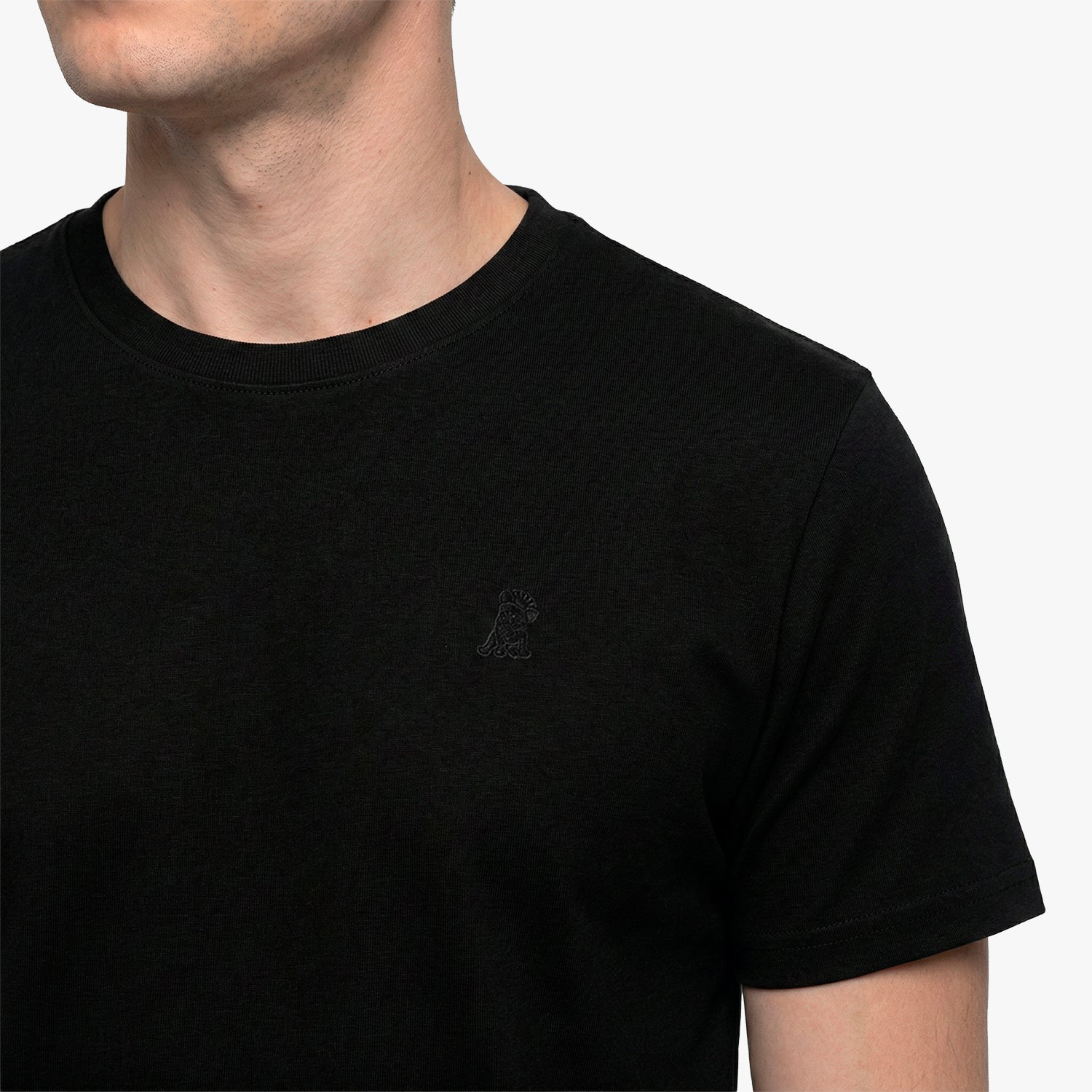 Close-up of a black t-shirt with a small logo on a plain background