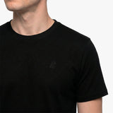 Close-up of a black t-shirt with a small logo on a plain background