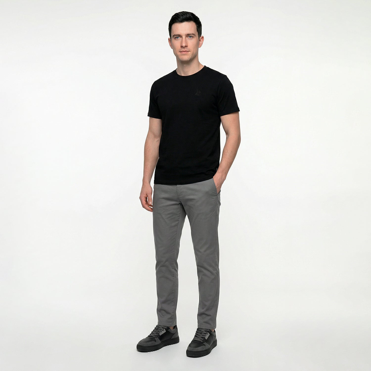 Man wearing a black t-shirt and gray pants on a white background