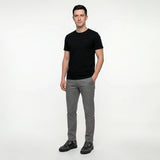Man wearing a black t-shirt and gray pants on a white background