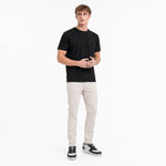 Man wearing a black t-shirt and light-colored pants on a white background