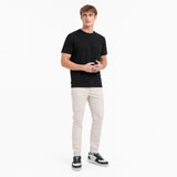 Man wearing a black t-shirt and light-colored pants on a white background