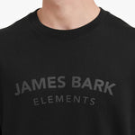 Close-up of a black t-shirt with 'JAMES BARK ELEMENTS' text on a white background