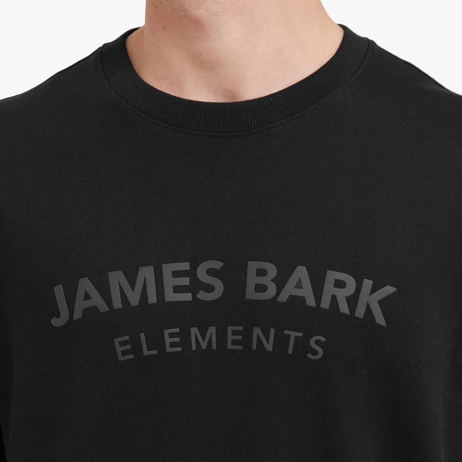 Close-up of a black t-shirt with 'JAMES BARK ELEMENTS' text on a white background