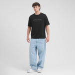 Man wearing a black t-shirt with 'James Bark' logo and light blue jeans on a white background