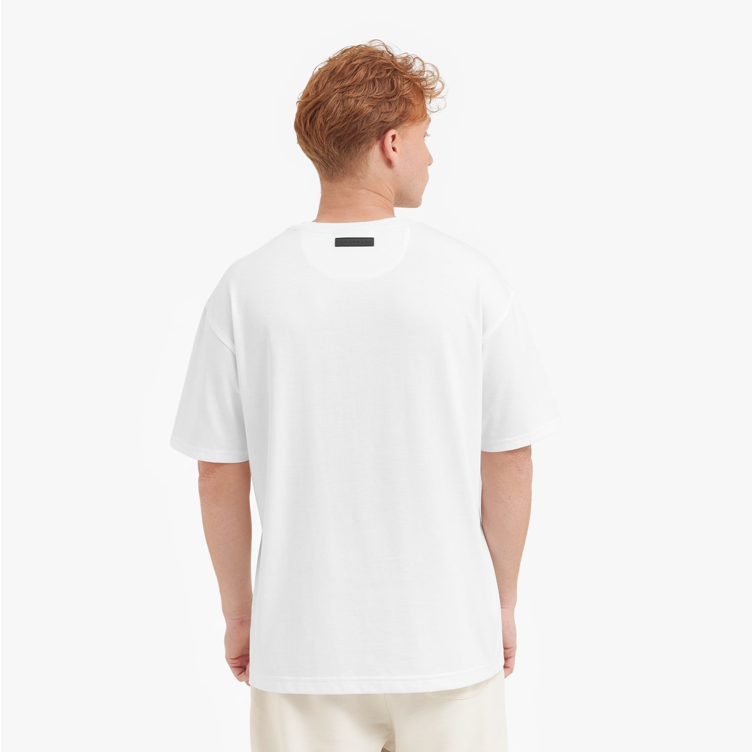 Back view of a man wearing a white t-shirt on a plain background