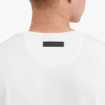 Close-up of a white t-shirt with a black label on the back, on a plain background