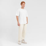 Person wearing a white t-shirt and cream pants on a plain background