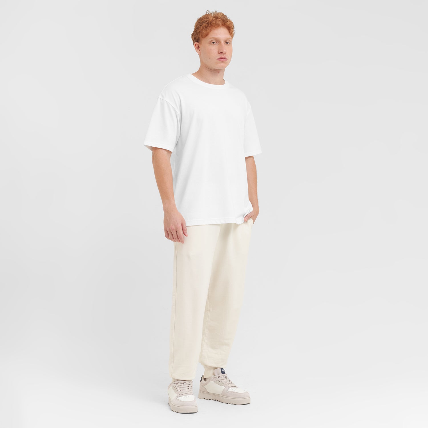 Person wearing a white t-shirt and cream pants on a plain background
