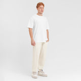Person wearing a white t-shirt and cream pants on a plain background