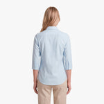 Woman wearing a light blue shirt and beige pants on a white background