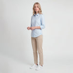 Woman wearing a light blue shirt and beige pants on a white background