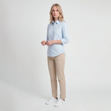Woman wearing a light blue shirt and beige pants on a white background