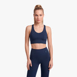 Woman wearing a navy blue sports bra and leggings on a light gray background
