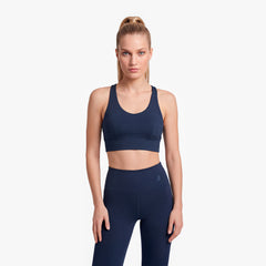Woman wearing a navy blue sports bra and leggings on a light gray background