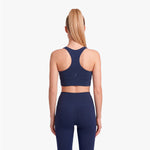 Woman wearing a navy blue sports bra and leggings on a white background