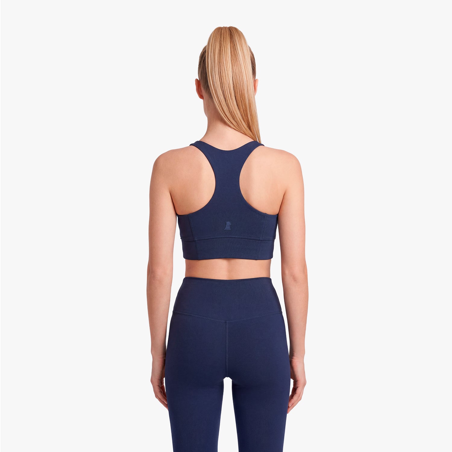 Woman wearing a navy blue sports bra and leggings on a white background