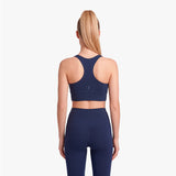 Woman wearing a navy blue sports bra and leggings on a white background