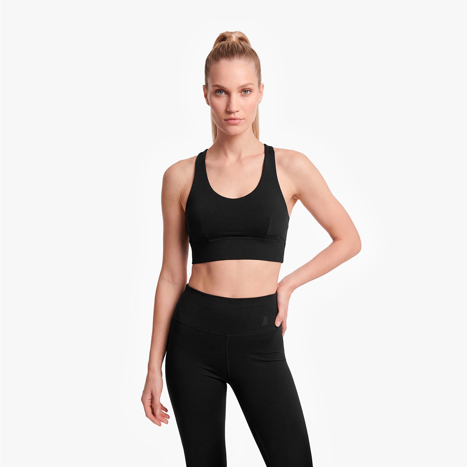 Woman wearing a black sports bra and leggings on a white background