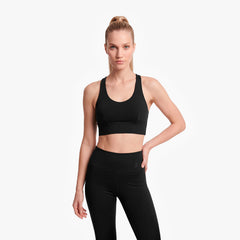 Woman wearing a black sports bra and leggings on a white background