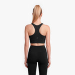Person wearing a black sports bra and leggings on a white background