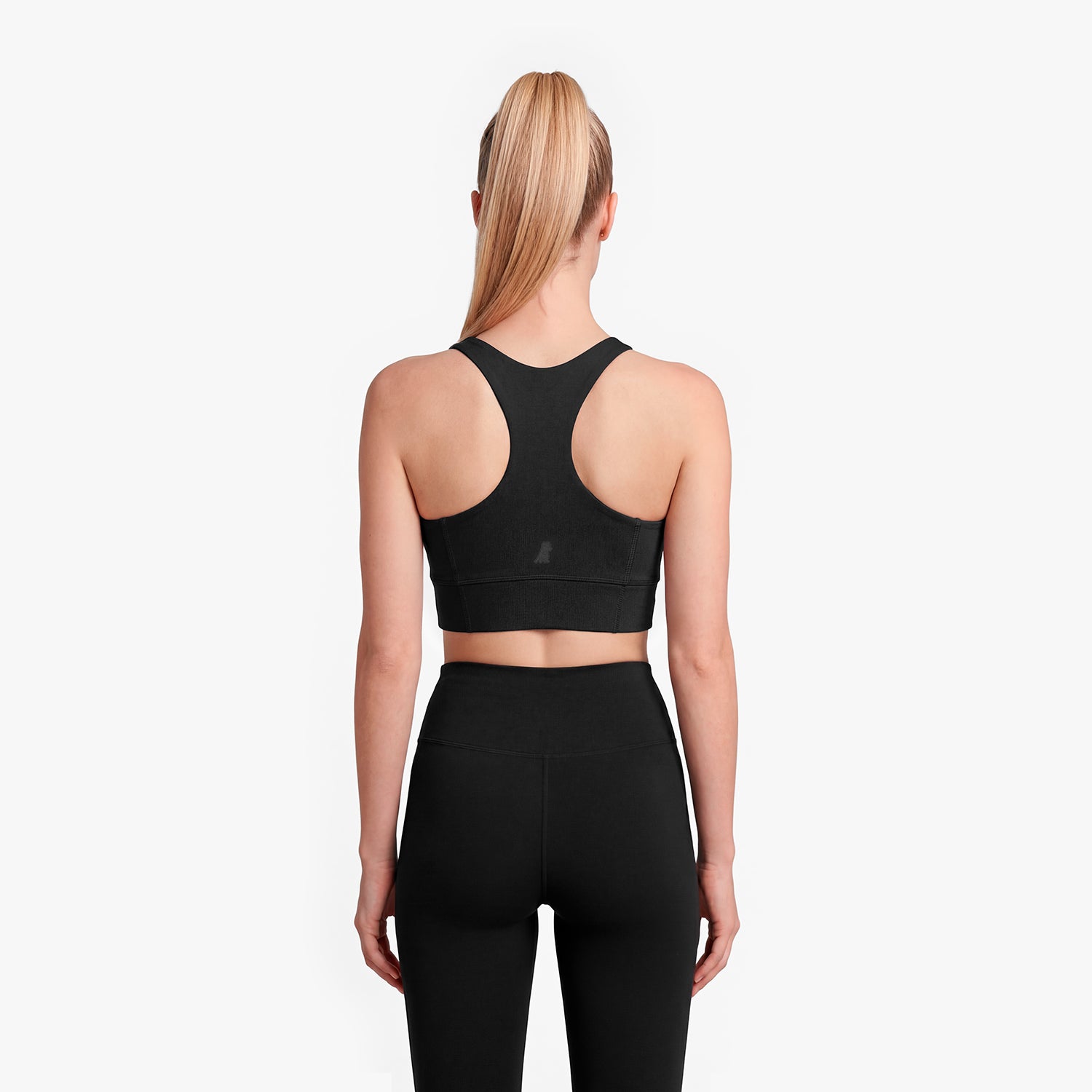 Person wearing a black sports bra and leggings on a white background