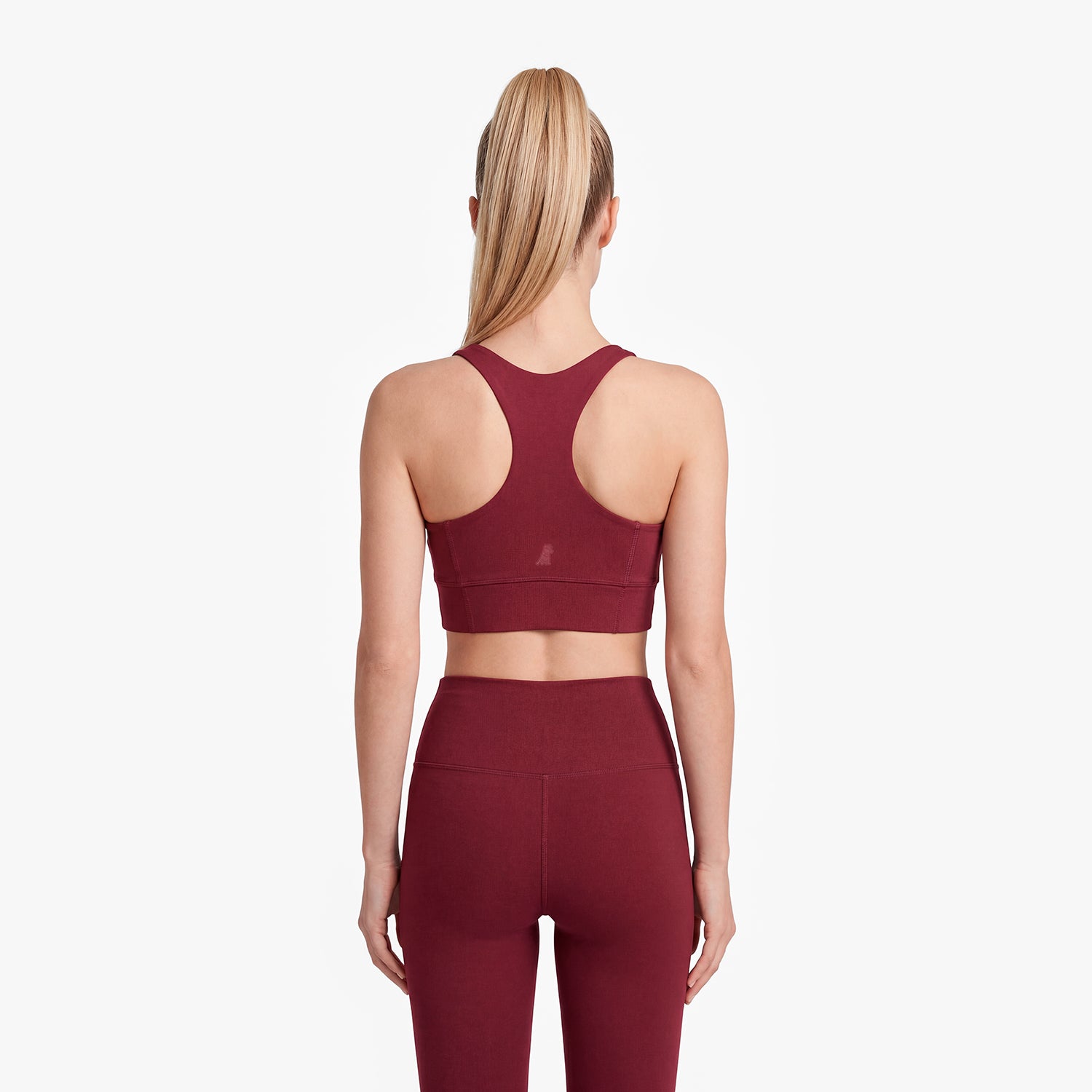 Person wearing a maroon sports bra and leggings on a white background