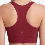 Maroon sports bra with open back on a neutral background