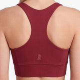 Maroon sports bra with open back on a neutral background