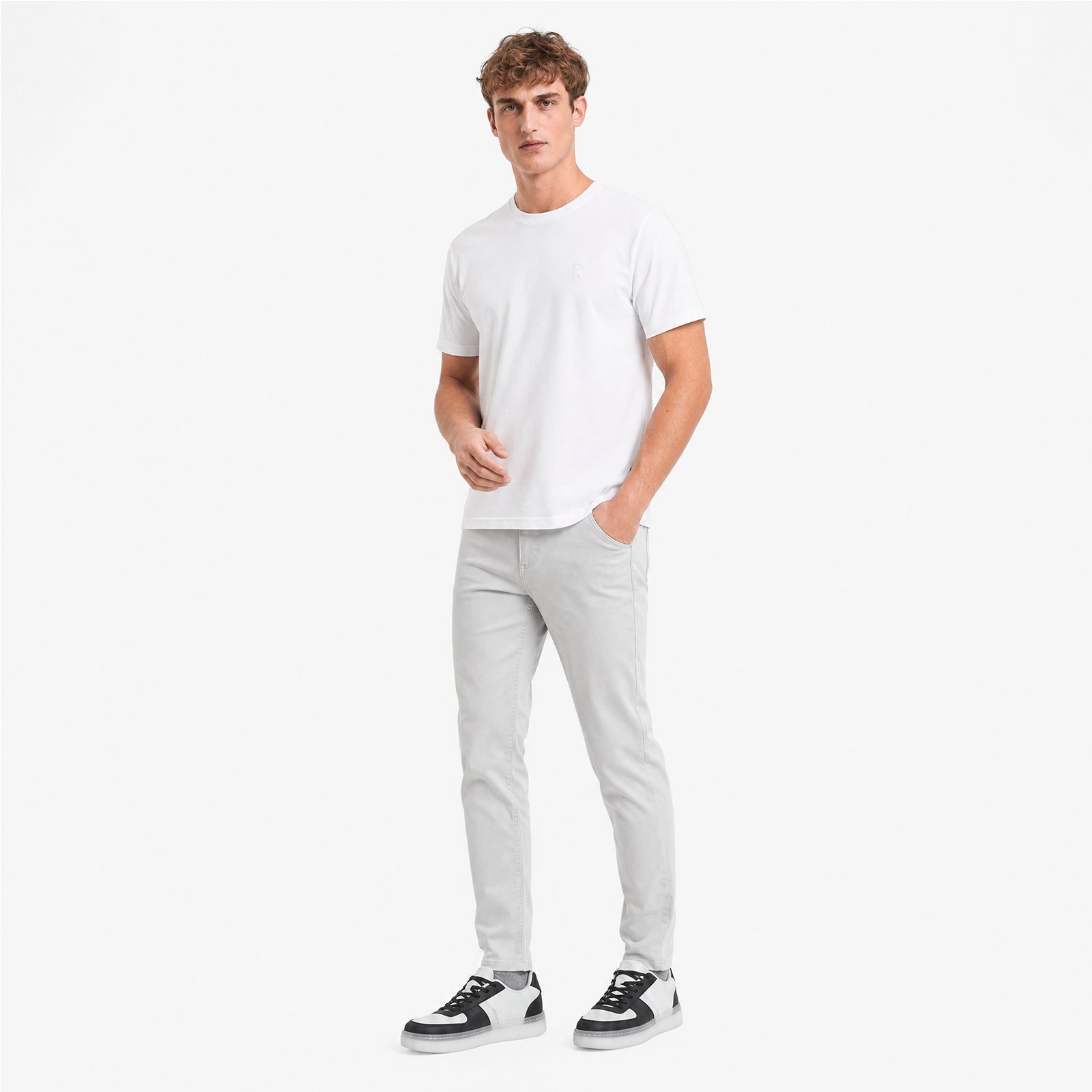 Man wearing a white t-shirt and light gray pants on a white background